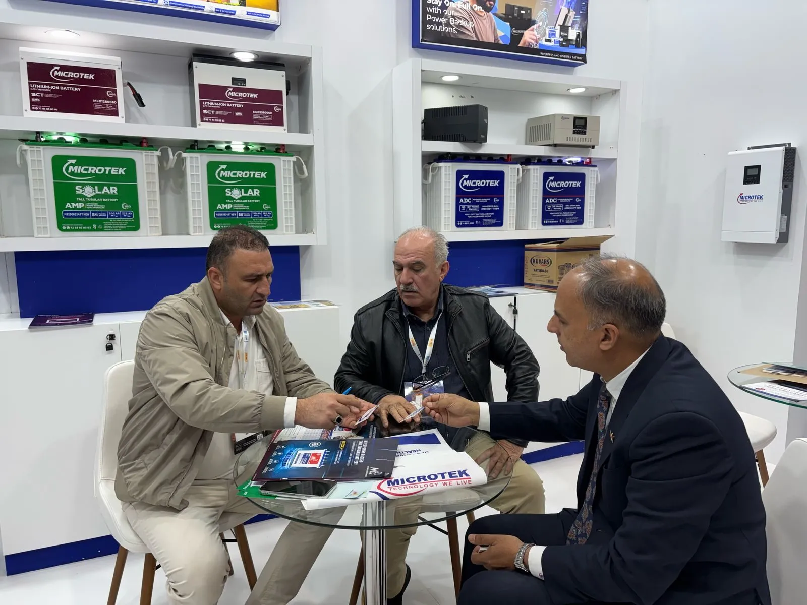 Microtek executive meeting prospective partners at the company's Turkey expo booth — Microtek Lithium-Ion and Solar battery range visible in the background